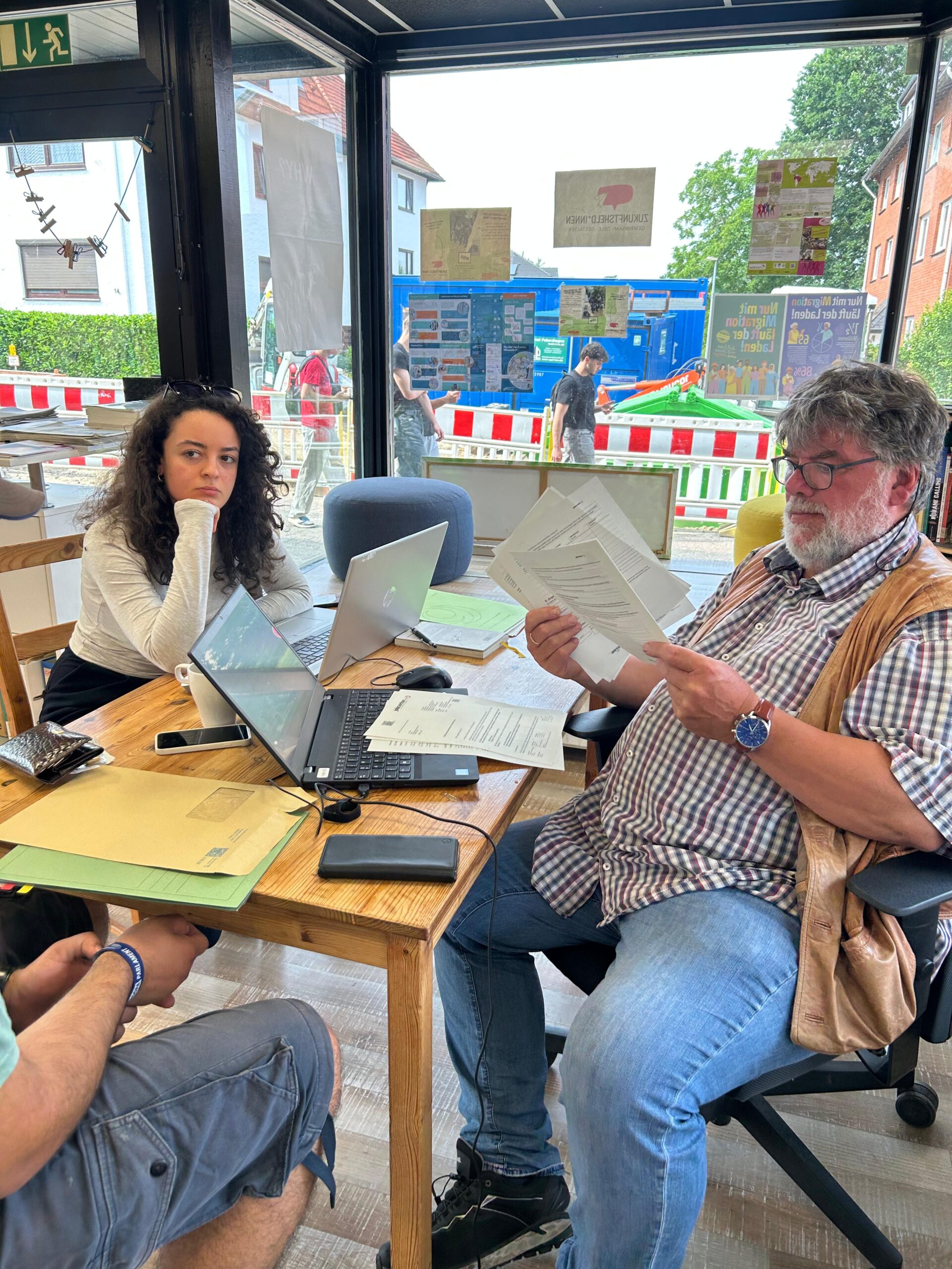 IMG-20250617-WA0025 Beratungssituation am Schreibtisch mit drei Menschen, Laptop und Papier