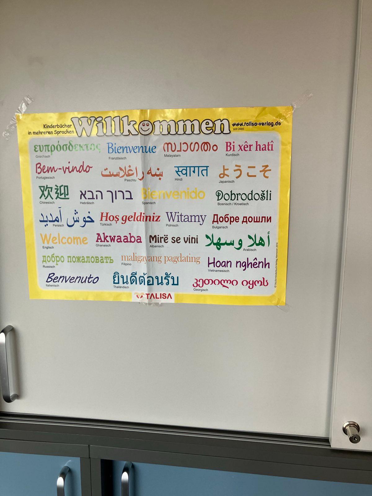 IMG-20251028-WA0019 Im Raum für den Sprachkurs hängt ein Plakat, welches das Wort Willkommen in vielen Sprachen zeigt