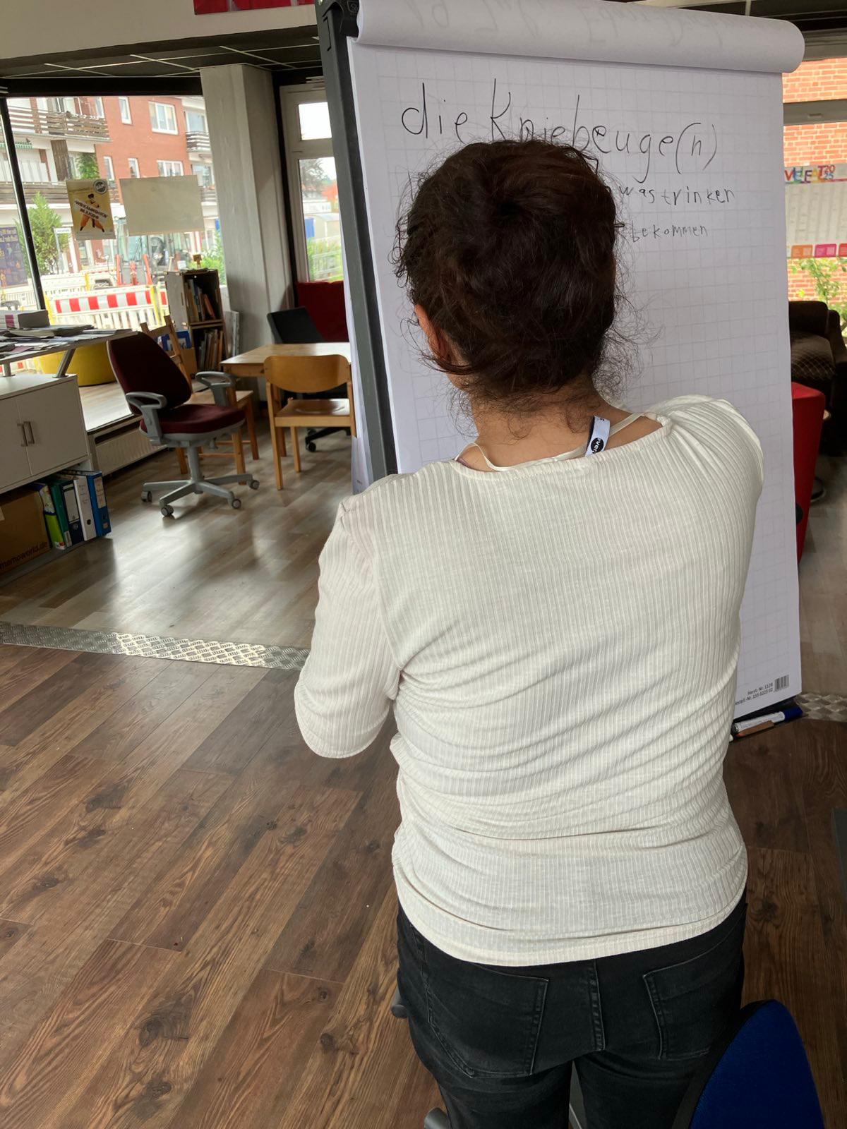 IMG-20251028-WA0021 Bein Sprachkurs schreibt eine Teilnehmende auf ein Flipchart