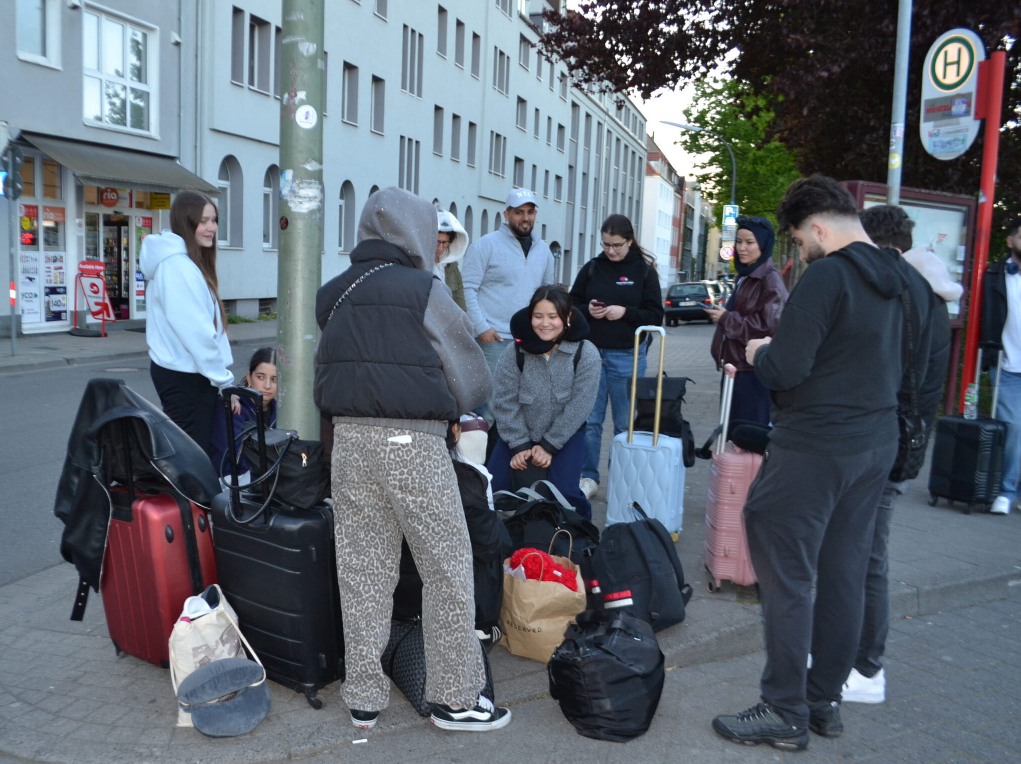 DSC_0003 Eine Gruppe Jugendlicher mit Gepäck wartet an einer Bushaltestelle auf die Abfahrt zu einem Ausflug