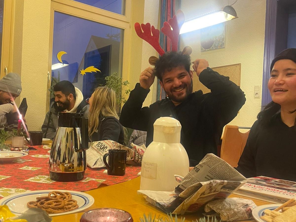 IMG_8454~photo Am vorweihnachtlichen Tisch haben Jugendliche Spaß, einer setzt eine Maske Rentier-Geweih auf